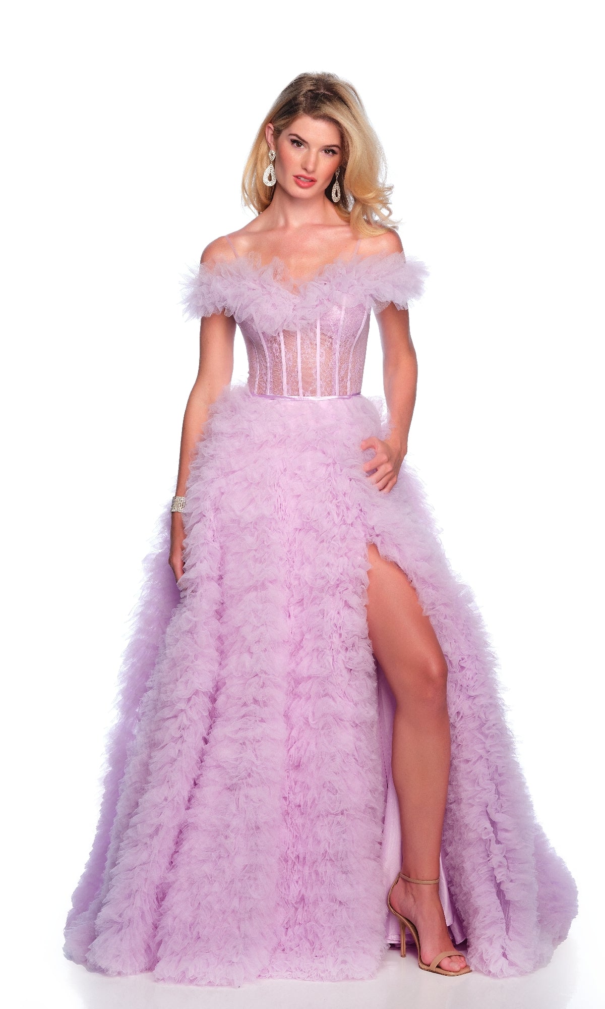 A woman stands against a white background in the Ruffled Lilac Prom Ball Gown: Dave & Johnny 12093, featuring an off-the-shoulder design, sheer corset bodice, feathered ball gown skirt, thigh-high slit, and high-heeled sandals.